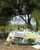 Idyllic, picturesque dining area under tree with sea view and table set in rustic style