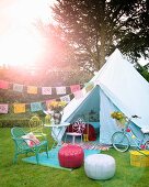 Feststimmung im Garten, Sitzplatz mit bunten Sitzmöbeln vor Zelt mit aufgehängten Girlanden