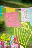 Romantic bunting with perforated bird motifs above pink cutlery basket in garden