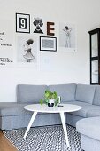 White, retro side table on black and white patterned rug in front of grey corner sofa