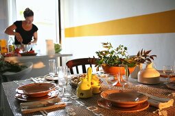 Gedeckter Tisch mit Weingläsern vor weisser Wand mit gelbem Streifen