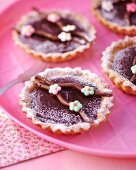Chocolate tartlets decorated with sugar flowers and icing sugar