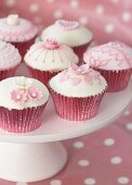 Decorated cupcakes in pink cases on white cake stand