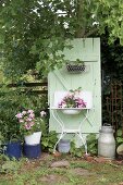 Planted, vintage washstand against mint-green board door in garden