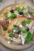 Pita bread topped with olives, rosemary, onions and sheep'S cheese