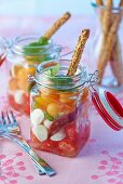 Melon and tomato salad with mozzarella and sesame seed sticks in preserving jars