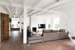 Elegant, pale grey sofa combination in open-plan interior with rustic charm, white, wood-beamed ceiling and pillars