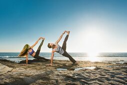 A couple practising yoga on a beach