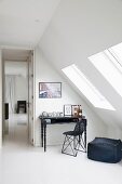 Black pouffe and chair at postmodern writing desk in attic room