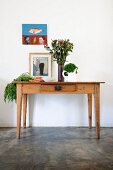 Vegetables and vase of flowers on rustic wooden table below picture on wall