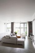 Pale grey corner in elegant living room with grey epoxy floor and view of lake