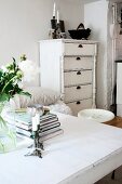 View across table to white chest of drawers with turned columns on front