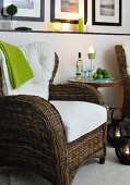 Wicker armchair with white cushions and side table with wine bottle and wine glasses in candlelight atmosphere