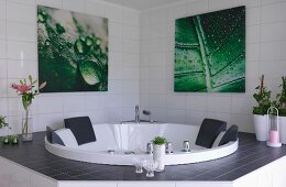 Eingebauter Whirlpool in weiss gefliestem Bad, an Wand Bilder mit Blattmotiv