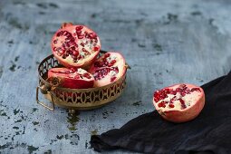 Pomegranate halves in a metal dish and next to it