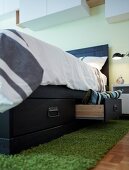 A dark grey wooden bed with storage drawers