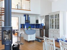 Scandinavian kitchen with island counter on castors in open-plan interior; free-standing log burner in foreground