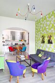 Colourful living area with patterned wallpaper and view into fitted kitchen in retro interior