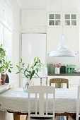 Detail of dining area; tablecloth on table below retro pendant lap with white, metal lampshade in rustic interior