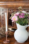 Sommerblumenstrauss in weißem Porzellankrug und Kerze in Kupfer Kerzenhalter