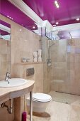 Elegant bathroom tiled in beige marble (Breccia Sarda) with purple ceiling panel