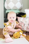 Baby sitting on floor playing with soft toy