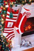 Gestrickte Nikolausstrümpfe an weihnachtlich dekoriertem Kaminsims