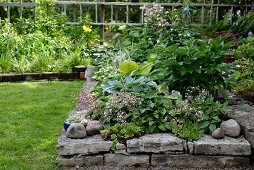Hochbeet mit Natursteineinfassung in sommerlichem Garten