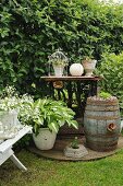 Nostalgische Gartenecke mit rustikalem bepflanztem Fass und dekorierter Vintage Tischnähmaschine