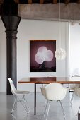 White classic chairs around dining table in front of modern artwork on wall in restored loft apartment