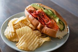 Brötchen mit gegrilltem Hummer, Avocado und Gurken, dazu geriffelte Kartoffelchips