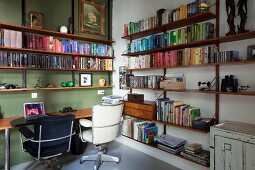 Black and white retro office chairs at desk in corner or room with green accent wall and bookcases