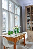 Wooden table with drawers and white Panton chairs in front of bookcase in traditional, period interior