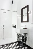 Sink on wrought iron sewing machine frame in white, modern bathroom with shower