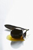 A black olive in a puddle of olive oil