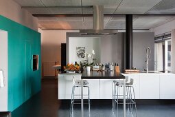 Kitchen island with adjoining table top and bar stools; fitted electrical appliances in turquoise custom cupboards