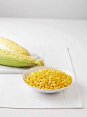 Raw corn cobs and a bowl of boiled sweetcorn