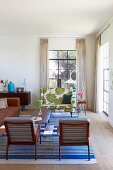 Living room with floor-length curtains on industrial-style windows and mixture of retro furnishings