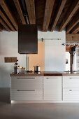 Kücheninsel, an Front geriffelte Metalloberfläche in loftartiger Wohnung mit rustikaler Holzdeckenkonstruktion