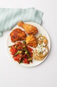 Fried chicken and roasted green tomatoes served with okra pods in tomato sauce