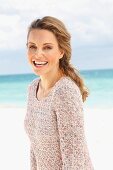 Blonde Frau in gestricktem Longpulli am Strand