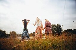 Three young women by a lake wearing hippie-style clothes