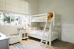 Weisses Etagenbett, daneben Nachtkästchen vor Fenster in Kinderzimmer