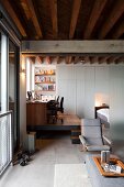 Loungeplatz vor Podest mit Schreibtisch, Bürostuhl und Bücherregal in der Ecke
