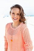 A young woman on a beach wearing an apricot coloured summer jumper