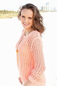 A young woman on a beach wearing an apricot coloured summer jumper