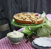Rhubarb tart with almonds on a cake stand served with whipped cream