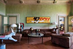 Gelbes Vintage Werbeplakat an lindgrün getönter Wand und Polstergarnitur in italienischem Renaissancebau