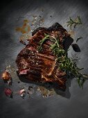 A grilled T-bone steak with rosemary, marinade and garlic