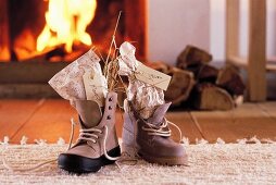 St. Nicholas gifts with name tags in laced boots in front of open fire